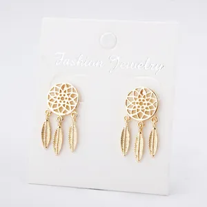 Détail de boucles d'oreilles dorées attrape-rêves avec de fins pendentifs plumes