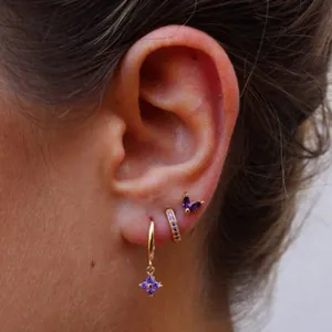 Parure de boucles d'oreilles trèfle et papillon violet doré portée sur l'oreille