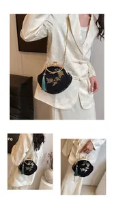 Detail of black Hanfu bag featuring golden floral embroidery and green silk tassel