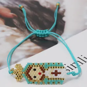Detailed macro view of woven blue Miyuki bead bracelet with Virgin Mary cross design