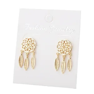 Boucles d'oreilles attrape-rêves bohèmes avec plumes dorées sur carte de bijoux blanche