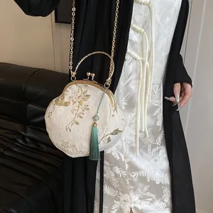 Close-up of Chinese retro style white satin bag with gold floral patterns and silk tassel