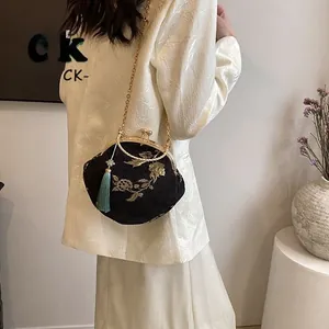 Close-up of black fabric bag featuring gold floral embroidery and light blue tassel detail