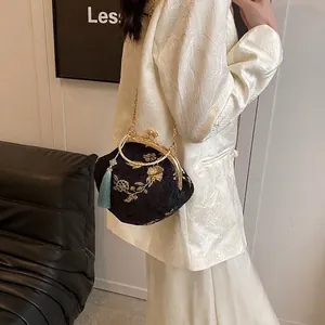 Detail of vintage black hanfu bag featuring gold floral embroidery and light blue tassel