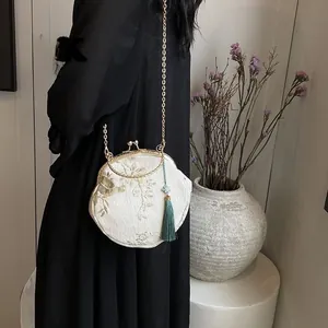 Detailed view of white floral embroidery on vintage satin bag with green tassel and chain