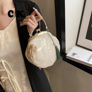 Detail of vintage beige velvet bag with gold embroidery, metal kiss lock and green tassel