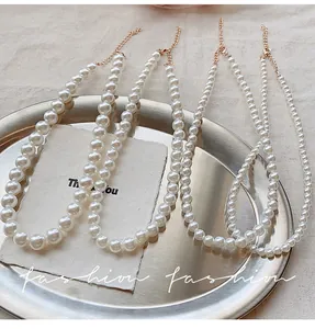 Detail of assorted pearl necklaces with golden lobster clasps on a stainless steel tray