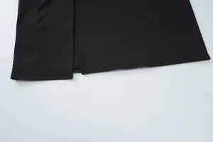 Detailed close-up of the black dress hemline featuring a clean side slit and stitching