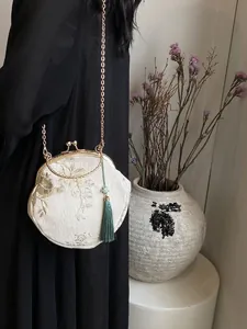 White Hanfu style crossbody bag with gold floral embroidery and teal tassel detail