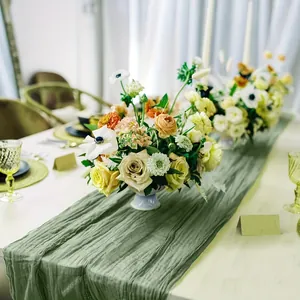 Close-up of sage green cheesecloth table runner with rustic wrinkled texture for weddings