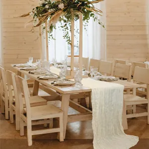 Close-up of ivory cheesecloth table runner with natural wrinkles on a wooden wedding table