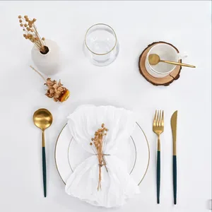 Elegant gold and dark green stainless steel cutlery set on white plates for table decor