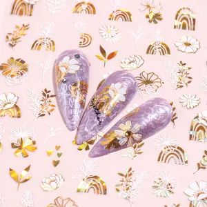 Nail art stickers with gold foil floral and leaf patterns on purple marble nails
