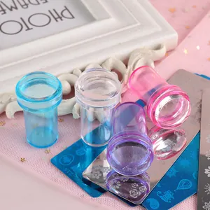 Detalle de cuatro sellos de uñas de silicona de colores y placas de metal grabadas
