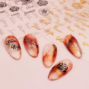 Macro detail of gold and silver rose nail stickers with script letters on amber nails