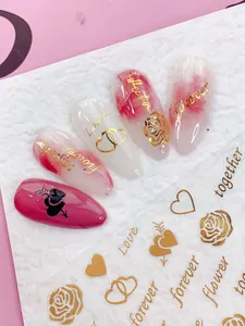 Detail of rose and heart nail decals with gold 'Love' lettering on pink marble manicure