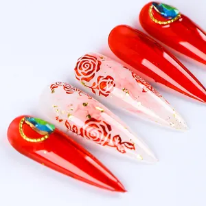 Dettaglio di unghie finte stiletto rosse e marmorizzate con foglia oro e rose art