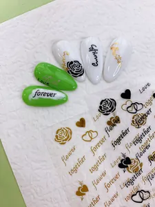 Detailed view of rose and heart nail art stickers with gold and black lettering designs