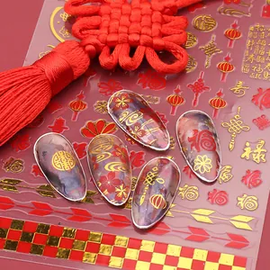 Makroaufnahme von roten und goldenen Nagelaufklebern mit Fú-Zeichen und Knoten