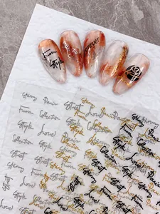 Detailed close-up of nail art stickers featuring gold and silver cursive text designs