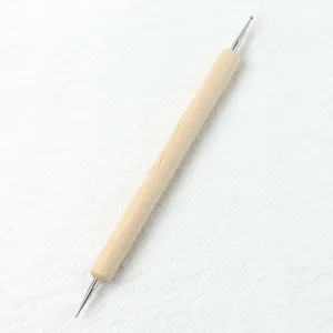 Macro detail of dual-head metal dotting tool with natural wood handle for nail art design