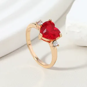Elegant gold-tone ring featuring a large heart-shaped red gemstone and side accents