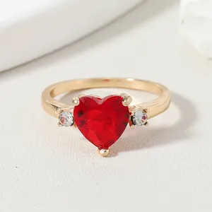 Elegant gold ring featuring a vibrant heart-shaped red gemstone and side diamonds