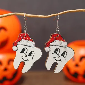 Orecchini natalizi a forma di dente in legno con cappello a pois su rami naturali