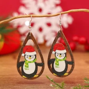 Vista macro de pendientes de madera con forma de gota y lindos pingüinos navideños