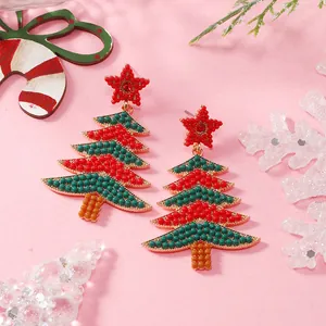 Dettaglio degli orecchini ad albero di Natale con perline e stella rossa su sfondo festivo