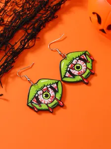Detail of Halloween drop earrings featuring green lips and bloodshot eyeball on orange backdrop