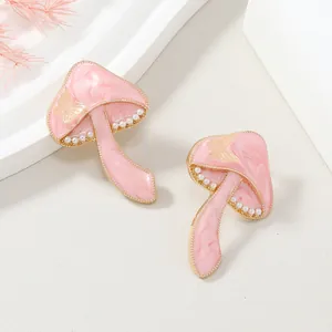 Detalle de pendientes de hongo rosa con mariposa dorada y micro perlas finas