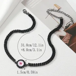 Close-up of black rhinestone choker with pink devil eye pendant and metal lobster clasp