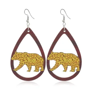 Close-up of teardrop wooden earrings featuring a leopard print bear cutout design