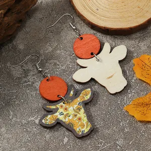 Dettaglio di orecchini in legno a testa di mucca con girasoli e decorazioni autunnali
