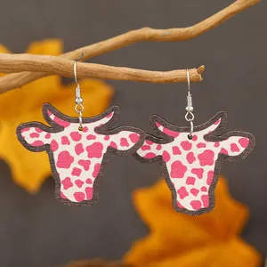 Orecchini a testa di toro con stampa mucca rosa su un ramo naturale con foglie autunnali