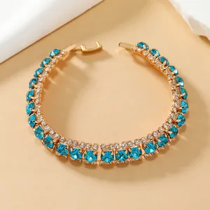 Detail van een bohemien gouden armband met blauwgroene kristallen en zirkonia's