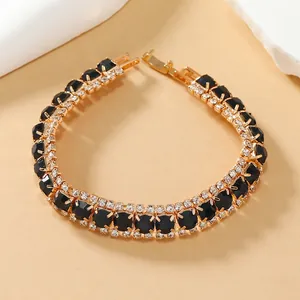 Detail van vergulde armband met zwarte gefacetteerde stenen en kristallen accenten