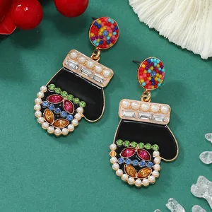 Dettaglio orecchini guanto di Natale con strass multicolore e perle su sfondo verde testurizzato
