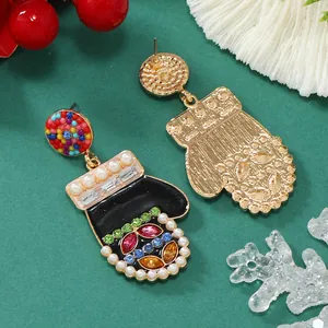 Dettaglio di orecchini a guanto di Natale con perle, gemme colorate e finitura dorata