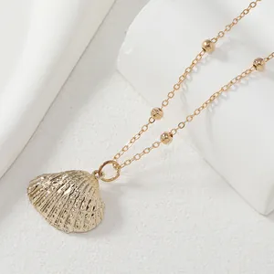 Collier pendentif coquillage doré avec chaîne perlée sur pierre, bijoux style côtier chic