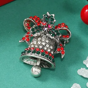 Dettaglio ravvicinato della spilla a campana di Natale con strass rossi e verdi e fiocco