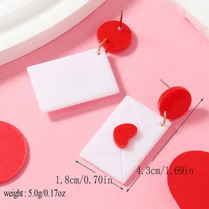 Vue détaillée des boucles d'oreilles enveloppe cœur avec mesures sur fond rose poudré