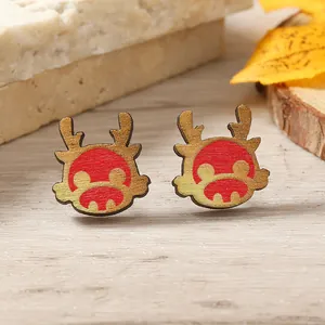 Cartoon style wooden reindeer stud earrings in red and gold finish on autumn wood background