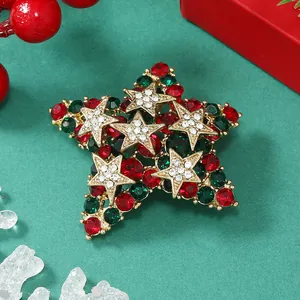 Dettaglio spilla a stella di Natale con strass rossi e verdi su base dorata