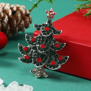 Vista dettagliata della spilla ad albero di Natale con strass rossi e verdi su pacco regalo