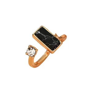 Adjustable gold ring with black marble stone and zircon crystal on white background