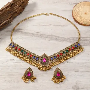 Ethnisches Schmuckset mit bunten Strasssteinen und goldenen Quasten auf Holzgrund