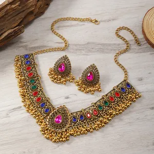 Ethno Schmuckset Gold mit bunten Edelsteinen und Quasten auf Holz Hintergrund