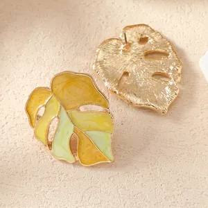 Détail de boucles d'oreilles Monstera en alliage doré avec émail dégradé vert